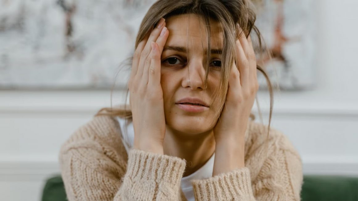 Woman looking distressed with hands on head, expressing worry indoors.